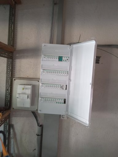 coffret aux normes Armoire électrique avec plusieurs disjoncteurs ouverte contre un mur.