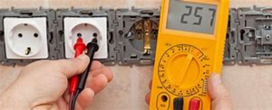 Mesure de tension sur une prise avec un multimètre. Valeur affichée : 257 volts.