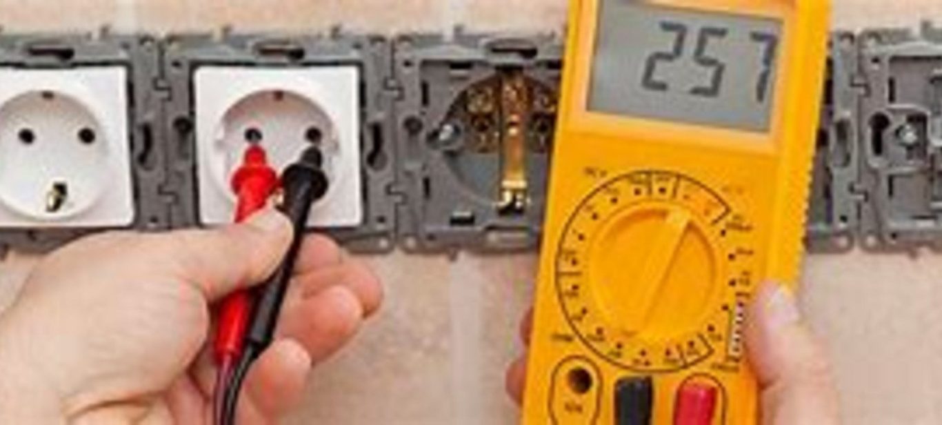 Prise électrique avec un multimètre, affichant une mesure de 257 volts.